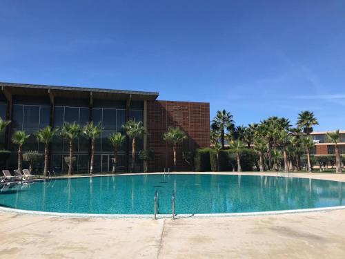 a large swimming pool in front of a building with palm trees at Salgados Beach in Albufeira
