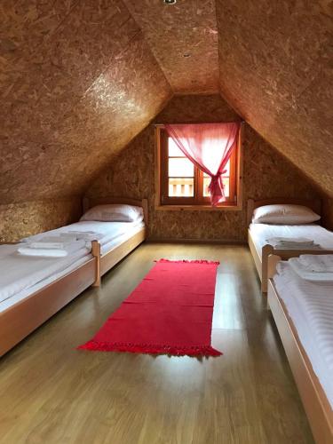 a attic room with two beds and a red rug at Domik in Mokra Gora