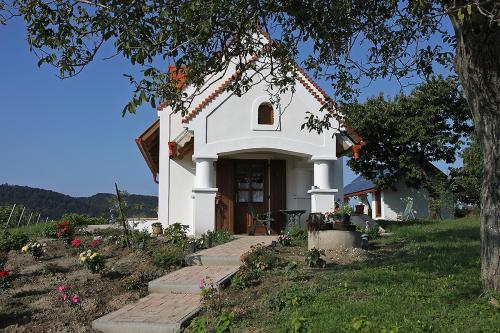 ein kleines weißes Haus mit einem Baum und Blumen in der Unterkunft Casa Beata in Lesencetomaj