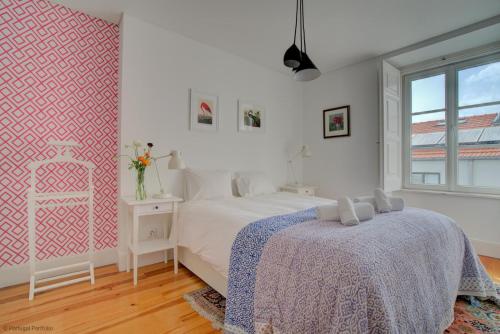 een witte slaapkamer met een bed en een raam bij Tracey & Neill's Place in Principe Real in Lissabon