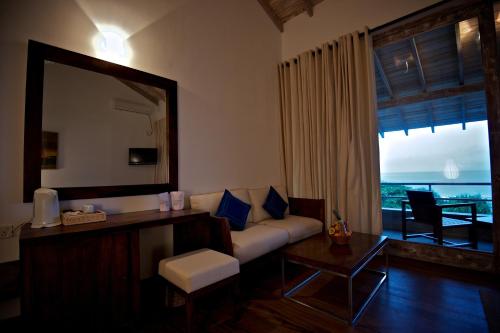 a living room with a couch and a mirror at Roman Beach Hotel in Hikkaduwa