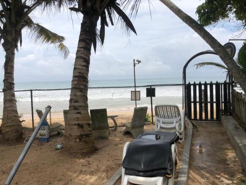 a beach with chairs and palm trees and the ocean at Sira's Chalets in Mirissa