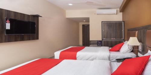 a hotel room with two beds and a flat screen tv at Plaza Hotel Trichy in Tiruchchirāppalli