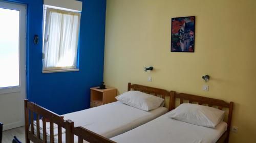 two beds in a room with a blue wall at Apartments Niksa Kastelan in Omiš