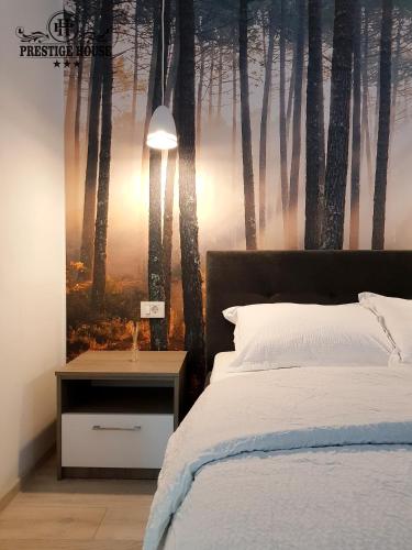 a bedroom with a bed with a painting of trees at Pensiunea Prestige House in Curtea de Argeş