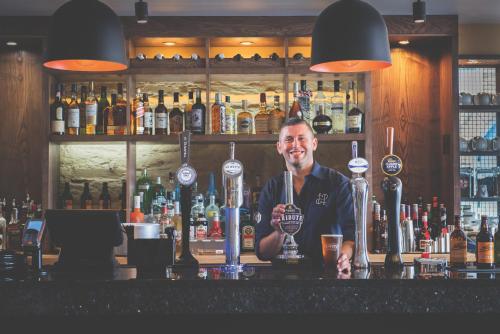 a man standing behind a bar with a trophy at Havener's in Fowey