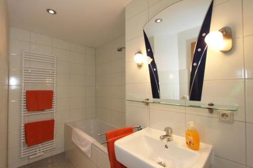 La salle de bains est pourvue d'un lavabo, d'un miroir et de serviettes orange. dans l'établissement Ferienwohnungen mit Weitblick, à Thale