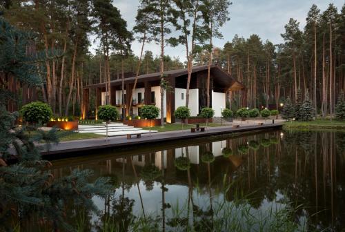 a house in the woods next to a pond at Verholy Relax Park in Sosnovka
