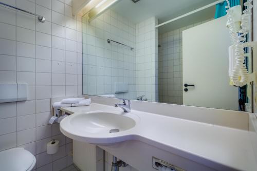 a white bathroom with a sink and a mirror at Hotel Astor in Altenburg