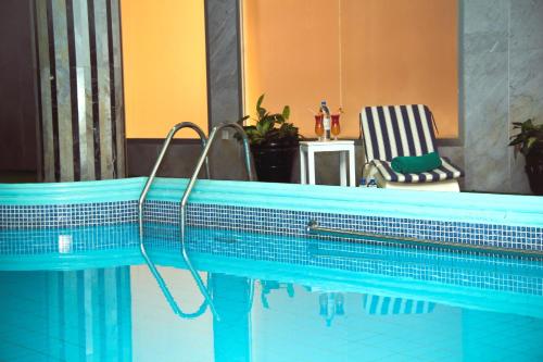 a blue swimming pool with a chair next to it at Nova Park Hotel in Sharjah