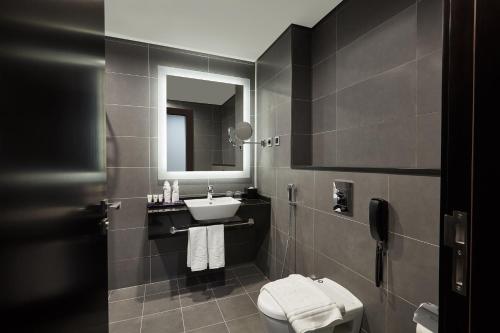 a bathroom with a sink and a toilet and a mirror at Park Regis Business Bay in Dubai