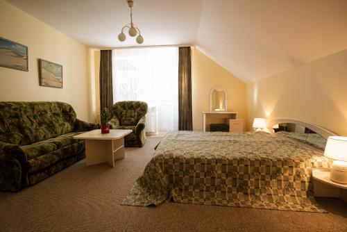 pokój hotelowy z łóżkiem i kanapą w obiekcie Egliu Slenis w mieście Juodkrantė