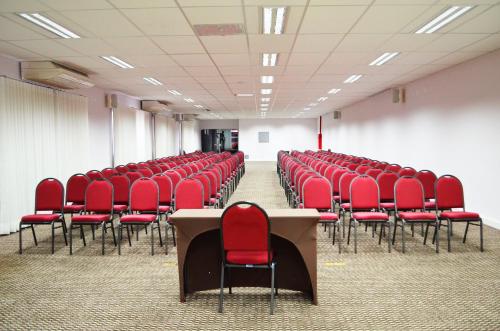 an empty room with red chairs and a table at Araçatuba Plaza Hotel in Araçatuba