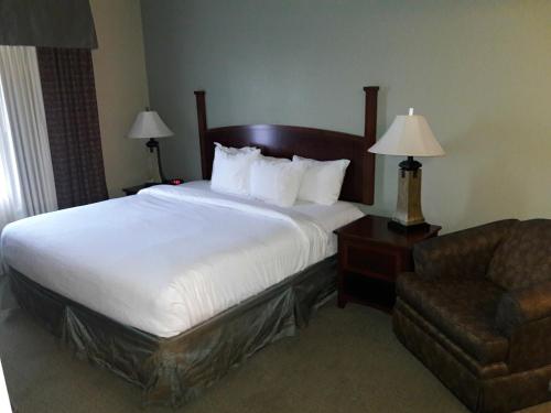 una habitación de hotel con una cama y una silla en WeStay Suites - Covington/Mandeville, en Covington