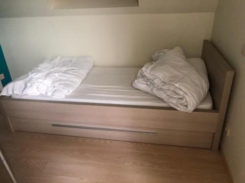 uma cama com lençóis brancos e almofadas em zeewinde em Middelkerke