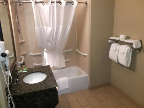 a bathroom with a tub and a sink and a shower at WeStay Suites - Covington/Mandeville in Covington