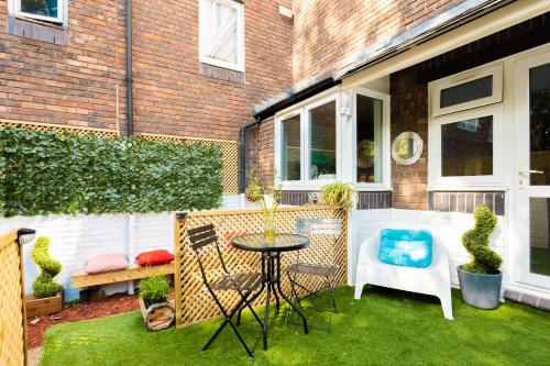 Un pequeño patio con una mesa y sillas en el césped. en Tower Bridge Rainbow Suites, en Londres