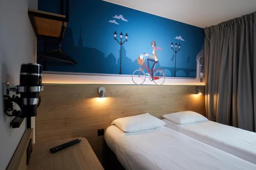 une chambre avec un lit et une peinture d'une femme sur un vélo dans l'établissement KYRIAD DIRECT Orleans - La Chapelle St Mesmin, à La Chapelle-Saint-Mesmin