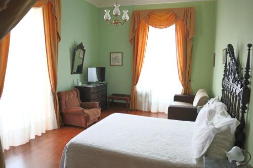 a bedroom with a bed and a chair and window at Alegre - Bussaco Boutique Hotel in Luso