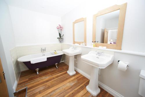 baño con 2 lavabos, bañera y espejos en The Bugle Inn Twyford, en Winchester