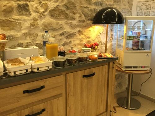 a kitchen with a counter with food and a refrigerator at Central Hotel in Nîmes