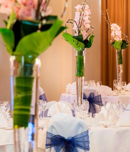 a table topped with white tables with vases filled with flowers at Park Inn by Radisson Palace in Southend-on-Sea