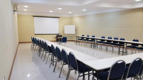 a conference room with tables and chairs and a whiteboard at Barbur Center Hotel in Ponta Grossa