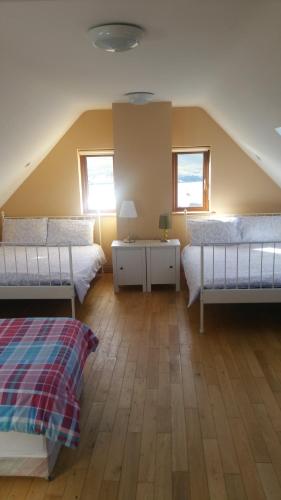 een slaapkamer op zolder met 2 bedden en 2 ramen bij Ocean View Doogort in Doogort