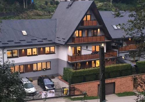 a large house with cars parked in front of it at Zakątek DoriMaks in Zawoja