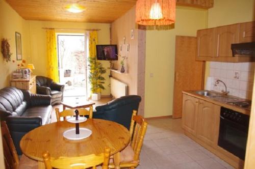 uma cozinha e sala de estar com uma mesa de madeira e cadeiras em -Waldhaus-Fewo 3 em Mirow