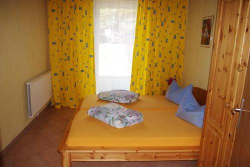 a room with two beds with yellow curtains and a window at -Waldhaus-Fewo 3 in Mirow