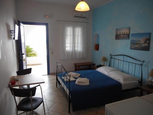 a bedroom with a blue bed and a table and chair at Pantonia Apartments in Agia Pelagia
