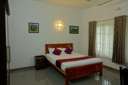 Un dormitorio con una cama con almohadas moradas y una ventana en Rose Cottage en Munnar