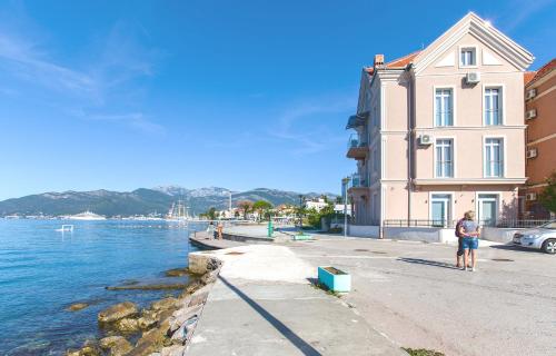 a man standing next to a building next to the water at Apartments Isja in Tivat