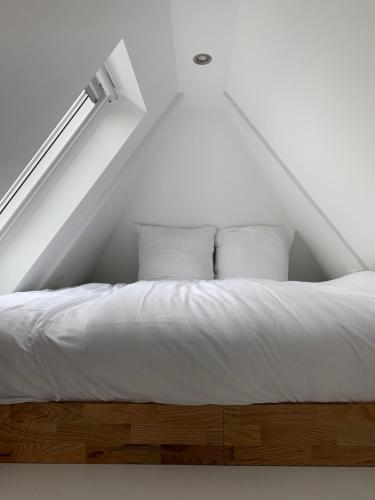 ein weißes Bett in einem Zimmer mit Fenster in der Unterkunft Payglop III in Alkmaar