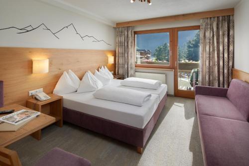 a hotel room with a bed and a chair at Hotel Alpenhof Kristall in Mayrhofen