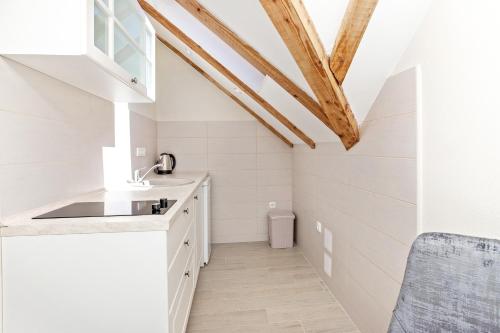 a kitchen with white walls and a wooden ceiling at Apartments Isja in Tivat