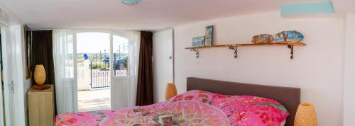 a bedroom with a bed with a pink comforter at little ibiza in Zandvoort