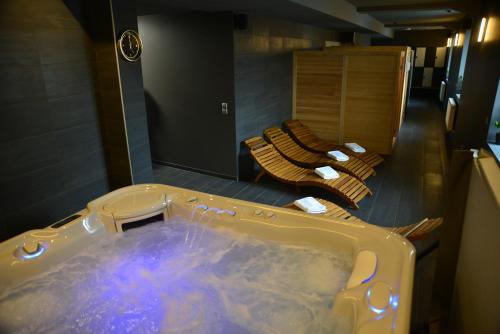 a bath tub in a bathroom with two lounges at Centrum Restauracyjno-Hotelowe Florres in Pawłowiczki