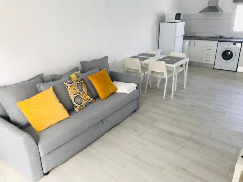 sala de estar con sofá gris y almohadas amarillas en Caleta Soul Apartment, en Puerto de Santiago