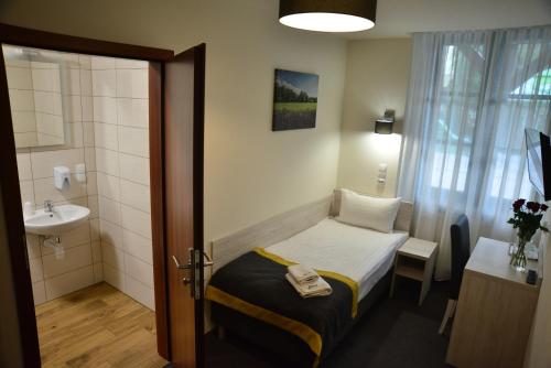 a small bathroom with a bed and a sink at Centrum Restauracyjno-Hotelowe Florres in Pawłowiczki