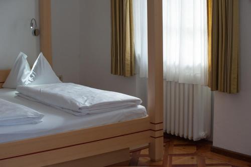 a bedroom with a bed with white sheets and a window at Parkhotel Sole Paradiso in San Candido