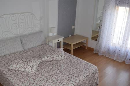 a bedroom with a bed and a table and a window at Casita de la Plaza . VUT-47-172 in Sardón de Duero