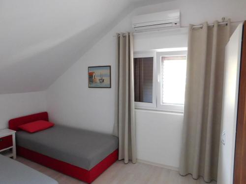 a small bedroom with a bed and a window at Villa Renata - Apartment Bijeli in Povlja