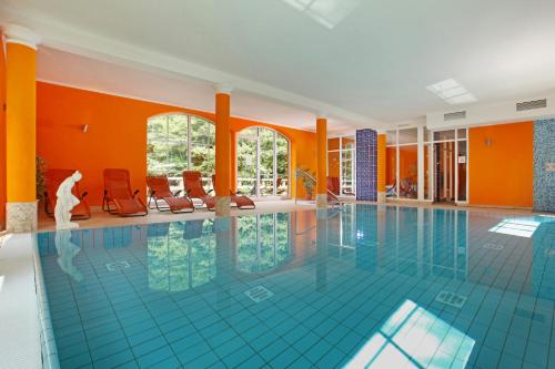 a swimming pool in a building with orange walls at Hotel Boltenmühle in Gühlen Glienicke
