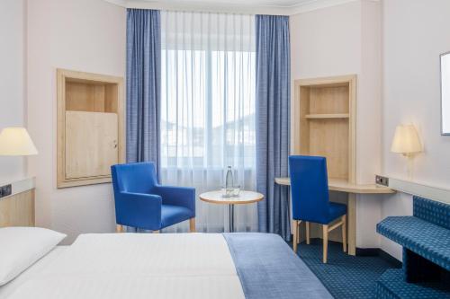 a hotel room with a bed and chairs and a table at IntercityHotel Erfurt in Erfurt