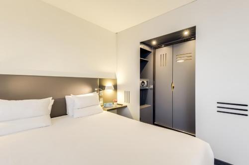 a bedroom with a large white bed and a door at Novotel Suites Paris CDG Airport Villepinte in Roissy-en-France