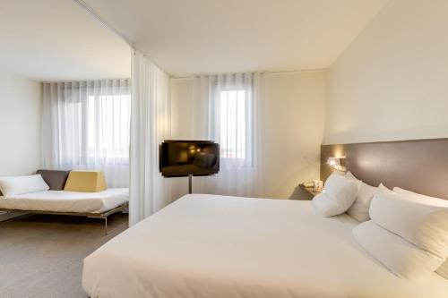 a bedroom with a large white bed and a tv at Novotel Suites Paris CDG Airport Villepinte in Roissy-en-France