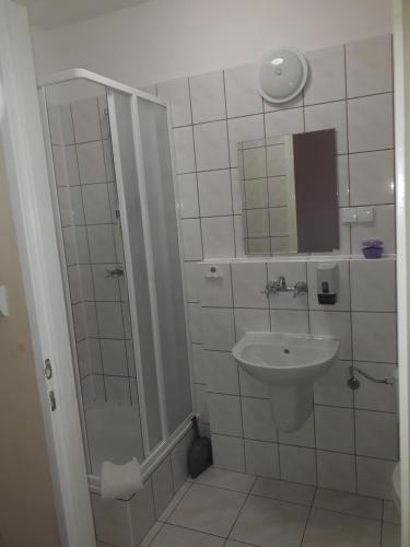 y baño blanco con lavabo y ducha. en Dom Pielgrzyma, en Góra Świętej Anny