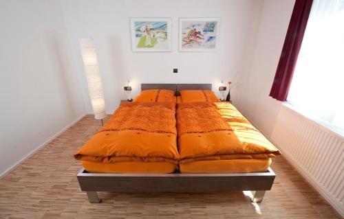 ein großes Bett mit orangefarbener Bettwäsche in einem Zimmer in der Unterkunft Hotel Merlin in Filderstadt